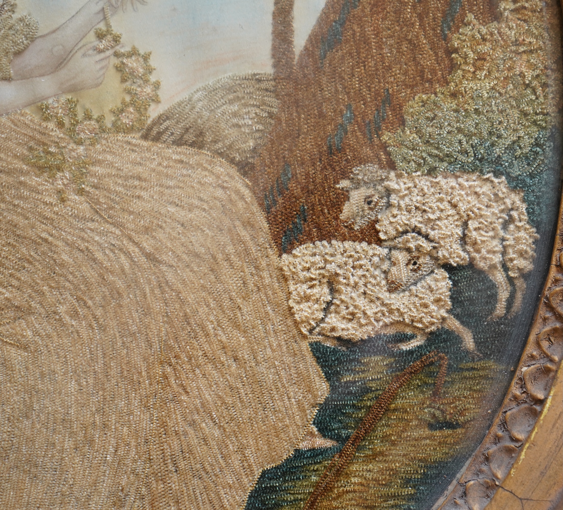 A pair of unusual early 19th century oval silk Chenille embroideries, one depicting a seated lady surrounded by a lion and donkey, the other depicting a seated shepherdess under tree with two sheep. Both have water colou